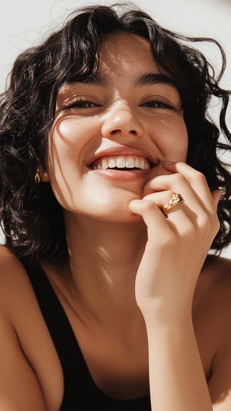A woman with natural curls smiling in warm sunlight